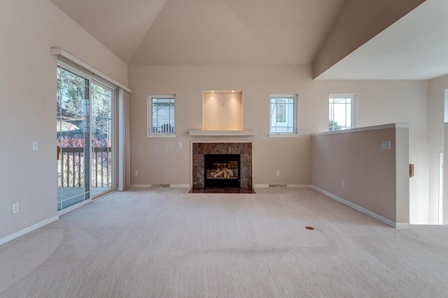 unfurnished living room featuring a wealth of natural light, baseboards, carpet, and vaulted ceiling