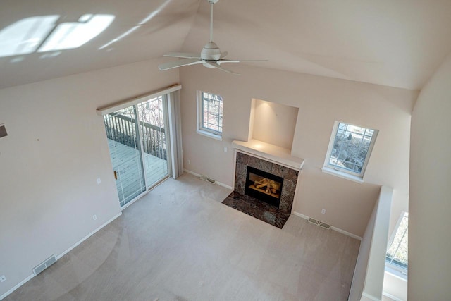 unfurnished living room featuring visible vents, lofted ceiling, a premium fireplace, and carpet flooring