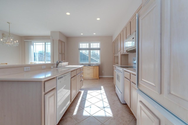 kitchen featuring white appliances, light tile patterned flooring, a wealth of natural light, and a sink