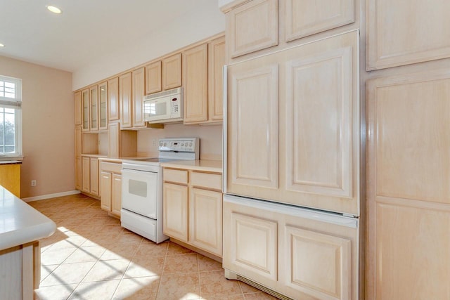 kitchen featuring light brown cabinetry, white appliances, light countertops, and light tile patterned flooring