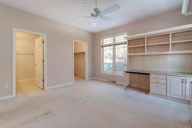 unfurnished office featuring light carpet, visible vents, baseboards, and built in desk