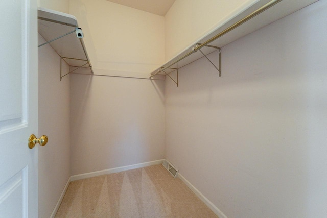 walk in closet with visible vents and light colored carpet