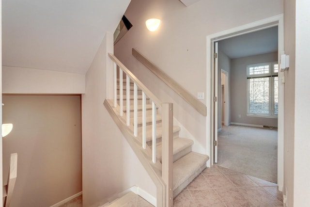 stairs featuring tile patterned flooring, baseboards, and carpet