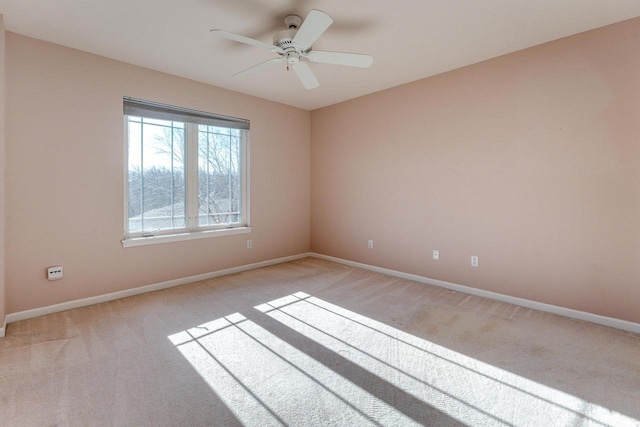 spare room with light carpet, a ceiling fan, and baseboards