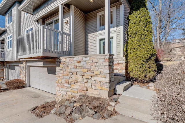 view of side of home with concrete driveway, an attached garage, and stone siding