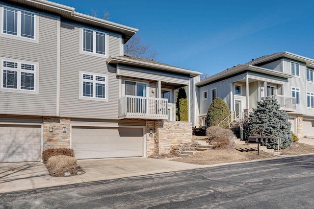 view of property featuring stone siding, driveway, and an attached garage