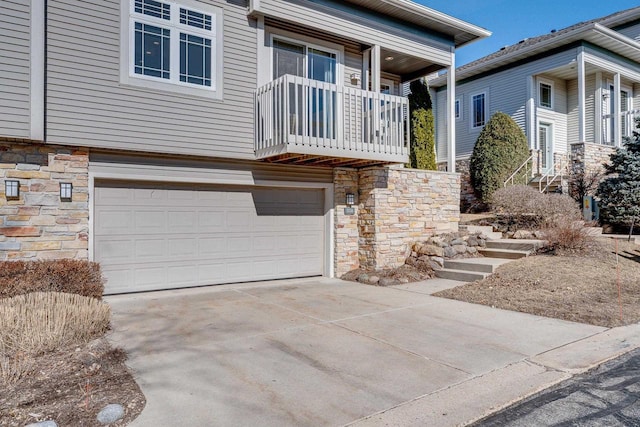 exterior space featuring stone siding, driveway, and a garage