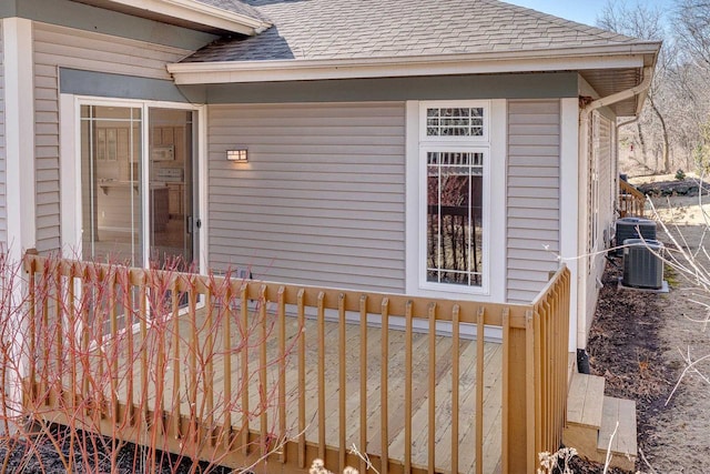 property entrance with cooling unit and a shingled roof