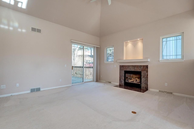 unfurnished living room featuring a premium fireplace, visible vents, and carpet floors