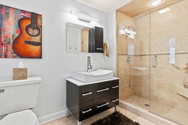 full bath with toilet, vanity, baseboards, tile patterned floors, and a stall shower