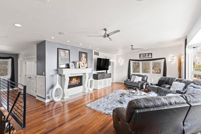 living area featuring visible vents, a ceiling fan, a fireplace with flush hearth, wood finished floors, and recessed lighting