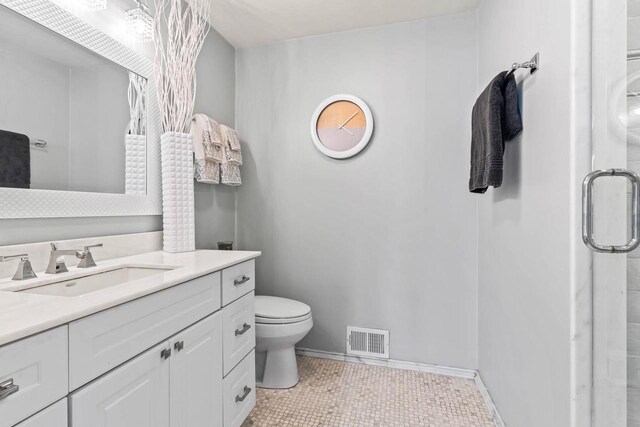 bathroom with toilet, a shower with shower door, visible vents, and baseboards