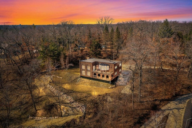 aerial view at dusk featuring a forest view