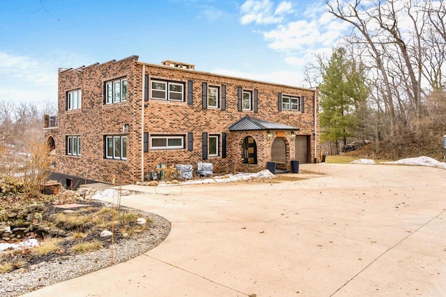 view of front of property with driveway, a garage, and brick siding