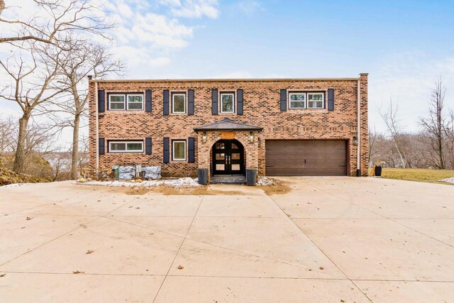 view of front of property featuring an attached garage, brick siding, concrete driveway, and french doors