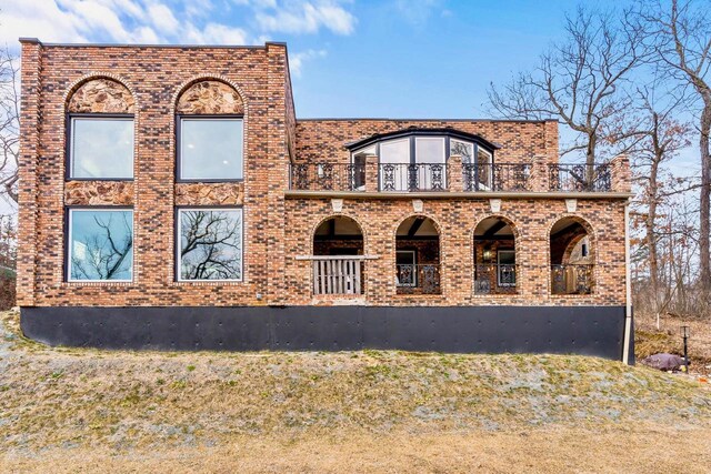 view of front of home with a balcony and brick siding