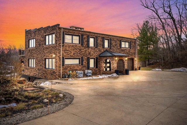 view of front of property featuring a garage, brick siding, and driveway