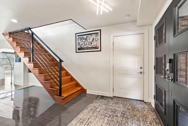 foyer entrance featuring stairs and baseboards