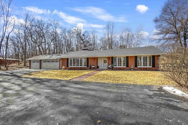 single story home featuring a front lawn, driveway, a garage, brick siding, and a chimney