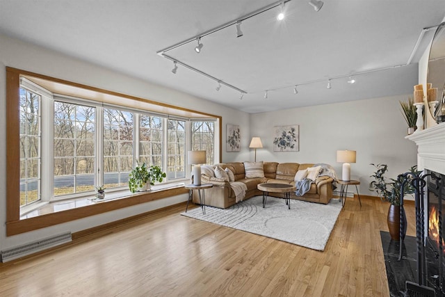 living room with visible vents, wood finished floors, baseboards, and a glass covered fireplace