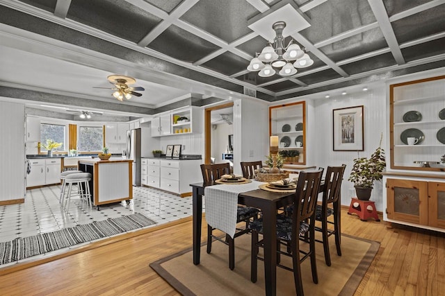 dining room featuring ceiling fan with notable chandelier, coffered ceiling, ornamental molding, and light wood finished floors