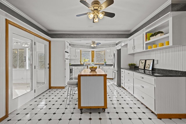 kitchen with stainless steel appliances, light floors, butcher block countertops, and crown molding