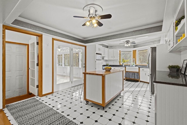 kitchen with ornamental molding, wood counters, freestanding refrigerator, white cabinets, and white microwave