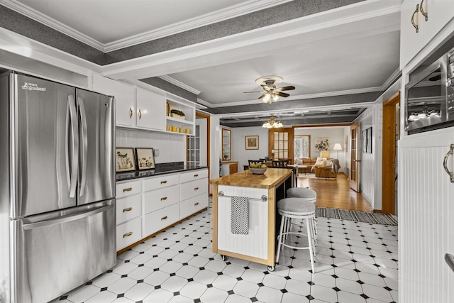 kitchen featuring light floors, butcher block counters, freestanding refrigerator, and crown molding