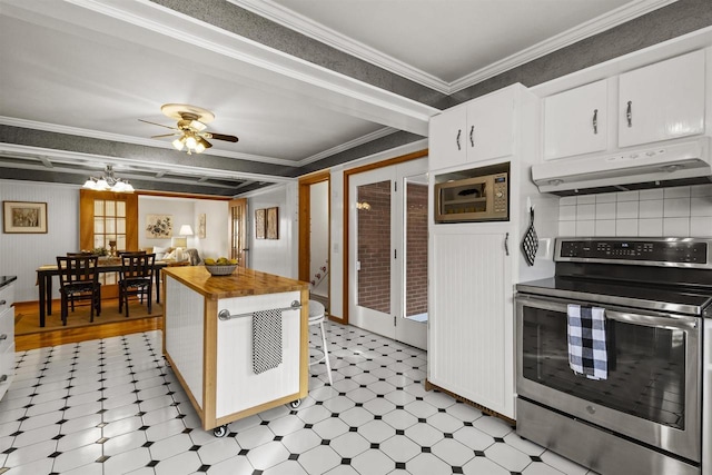 kitchen featuring butcher block countertops, ornamental molding, under cabinet range hood, appliances with stainless steel finishes, and light floors