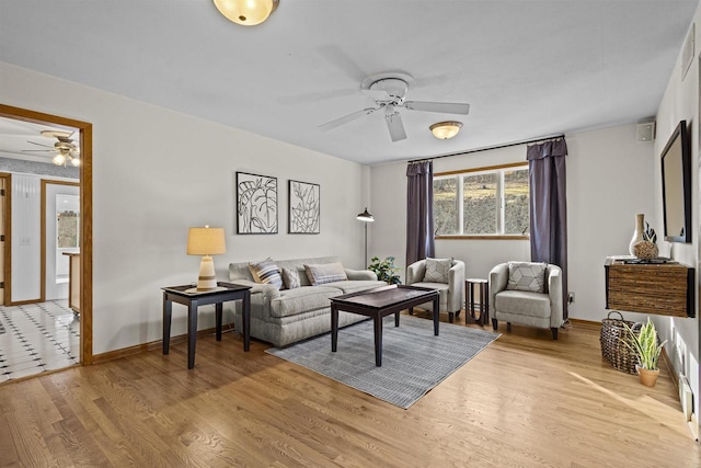 living area featuring a ceiling fan, light wood-style floors, and baseboards