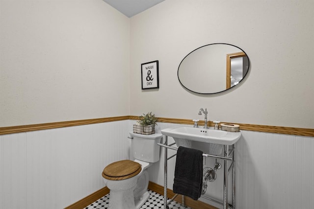 bathroom with a wainscoted wall, toilet, and a sink