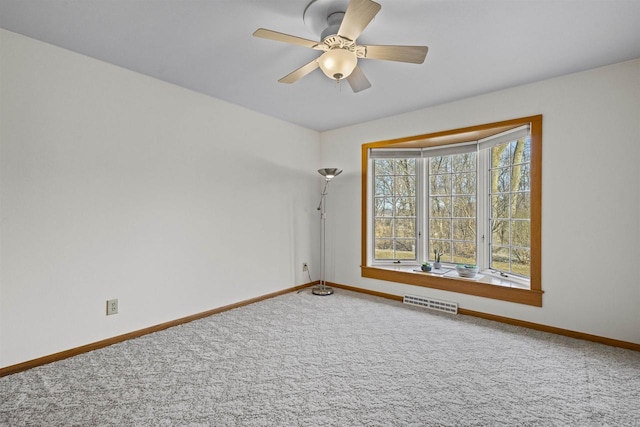 empty room with visible vents, a ceiling fan, baseboards, and carpet floors