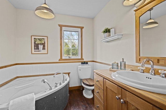 bathroom with vanity, a bath, a wainscoted wall, hardwood / wood-style flooring, and toilet