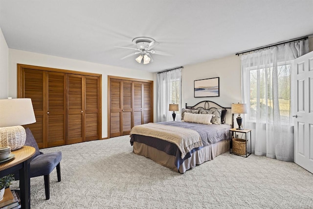 carpeted bedroom with two closets and a ceiling fan