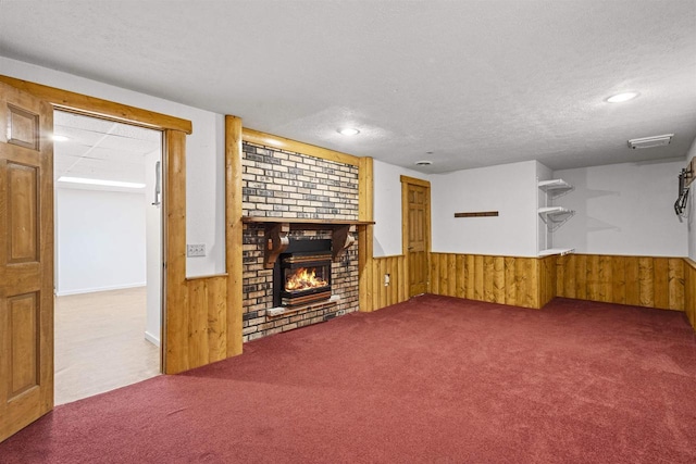 unfurnished living room featuring carpet flooring, a fireplace, wood walls, and wainscoting