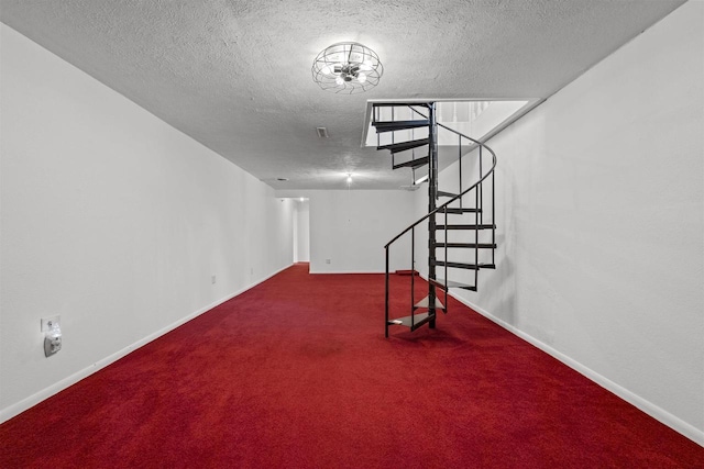 below grade area featuring visible vents, a textured ceiling, stairway, carpet, and baseboards