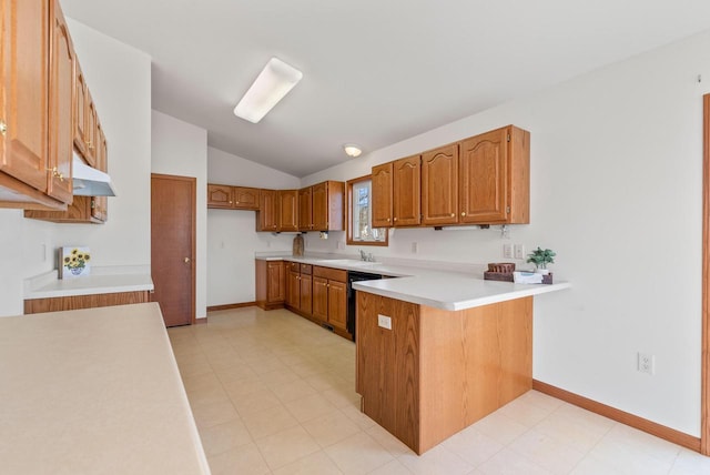 kitchen with a peninsula, light countertops, brown cabinets, and a sink