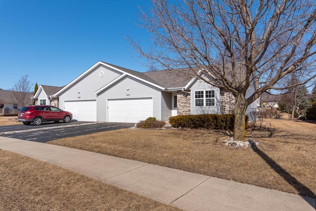 ranch-style house featuring aphalt driveway, an attached garage, and brick siding