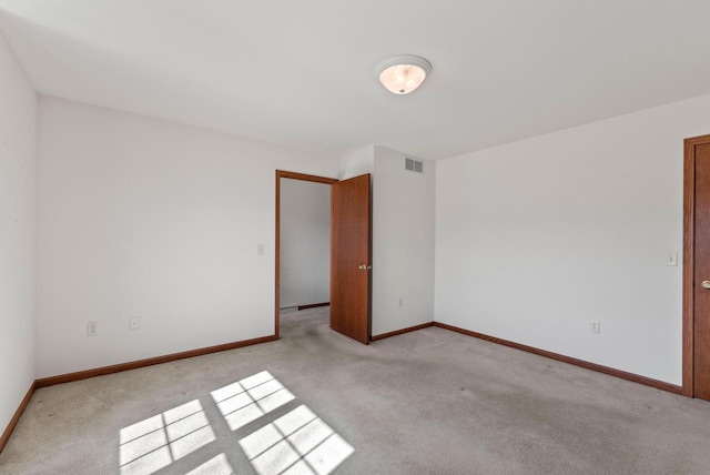 unfurnished room featuring visible vents, light colored carpet, and baseboards