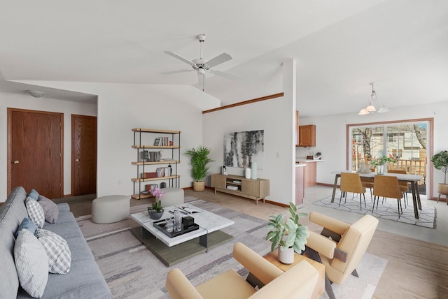 living area featuring lofted ceiling, ceiling fan with notable chandelier, and baseboards