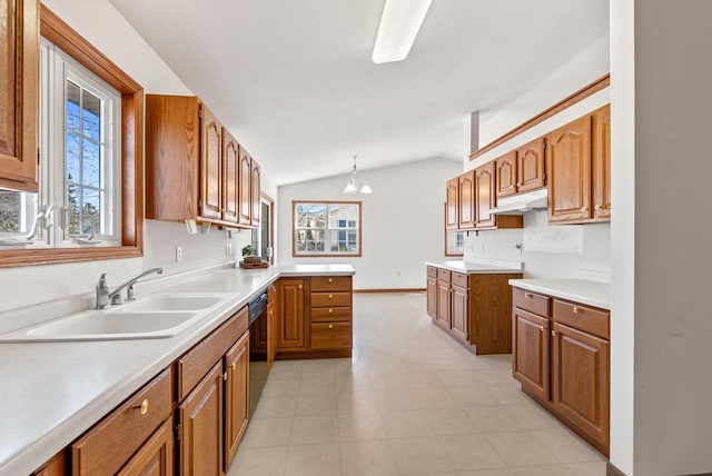 kitchen featuring vaulted ceiling, brown cabinets, and a sink