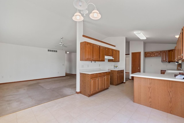 kitchen with visible vents, lofted ceiling, under cabinet range hood, ceiling fan with notable chandelier, and brown cabinets