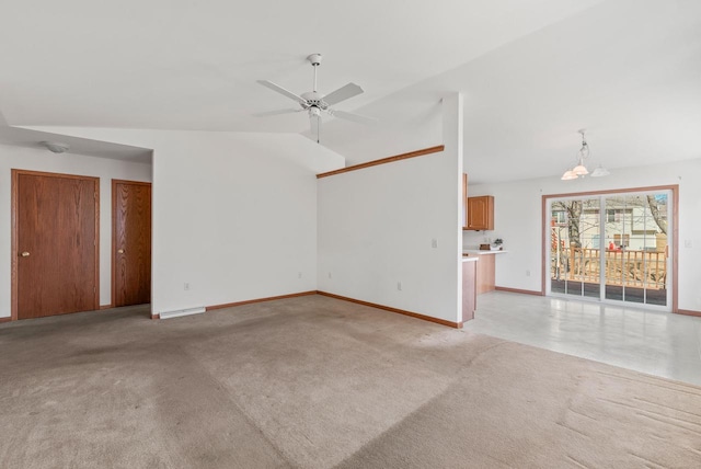 spare room featuring light colored carpet, ceiling fan with notable chandelier, baseboards, and vaulted ceiling