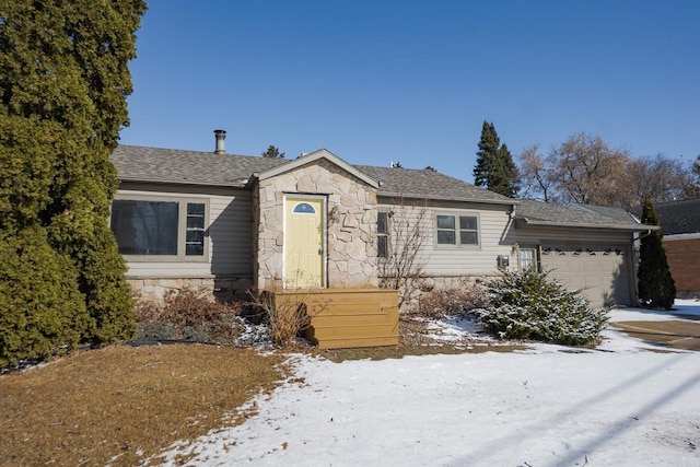 ranch-style home with a shingled roof, stone siding, and an attached garage