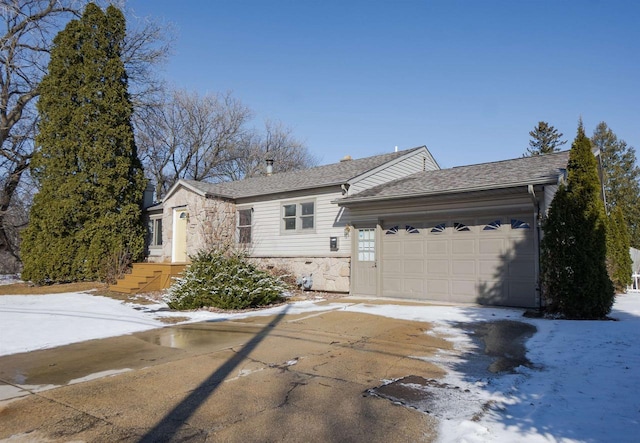 single story home featuring a garage, driveway, roof with shingles, and stone siding