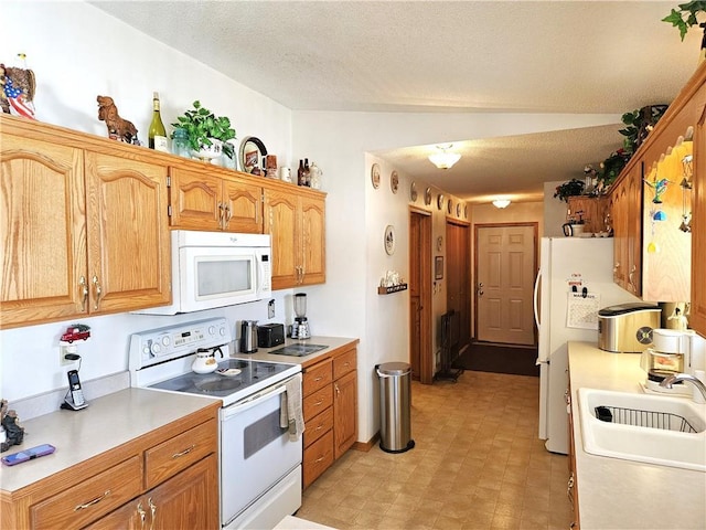 kitchen with a textured ceiling, white appliances, a sink, light countertops, and light floors