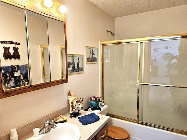 full bathroom with enclosed tub / shower combo, a textured ceiling, and vanity