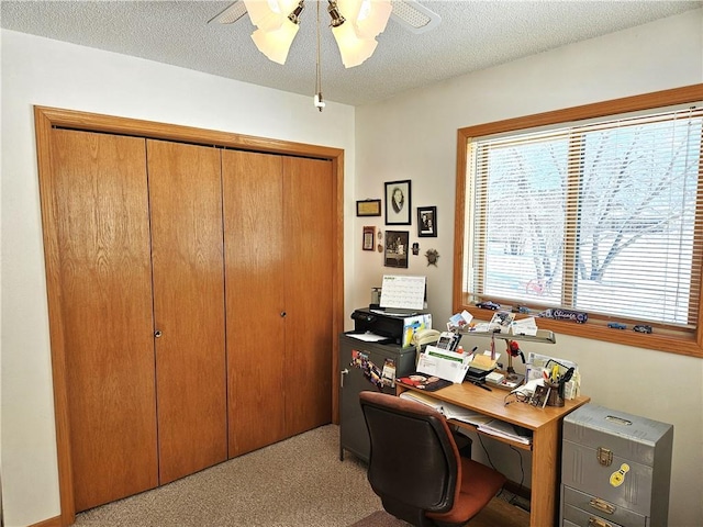 carpeted office space with a textured ceiling and a ceiling fan