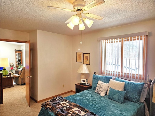 bedroom with light carpet, ceiling fan, a textured ceiling, and baseboards