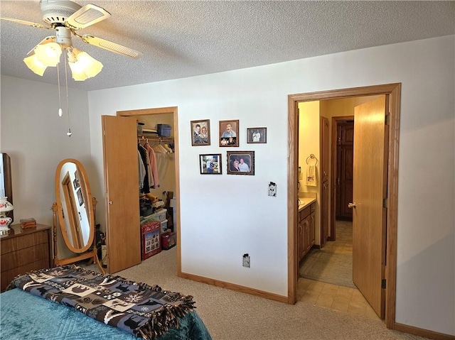 bedroom with baseboards, light colored carpet, a spacious closet, a textured ceiling, and a closet